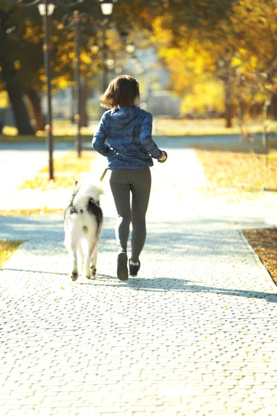 Mulher correndo com seu cão no parque — Fotografia de Stock