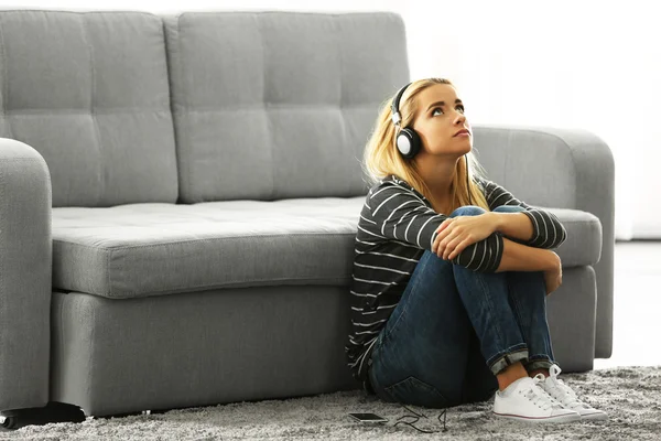 Młoda kobieta siedzi i słuchanie muzyki w pokoju — Zdjęcie stockowe