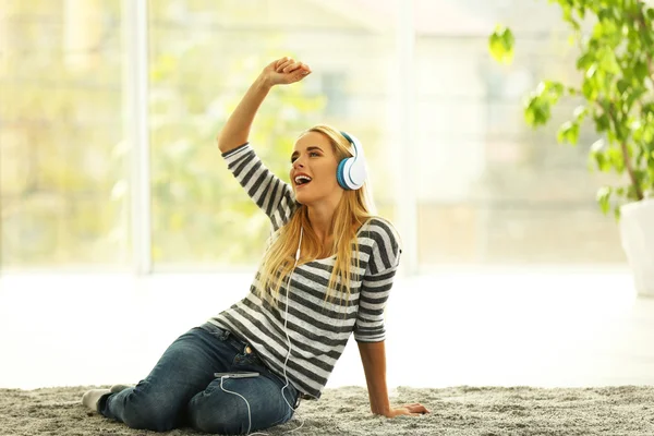 Jeune femme par terre dans une pièce écoutant de la musique — Photo