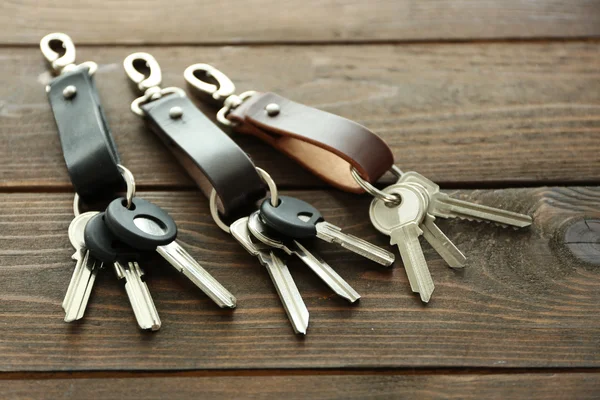 Keys attached to leather keychain , on wooden background — Stock Photo, Image