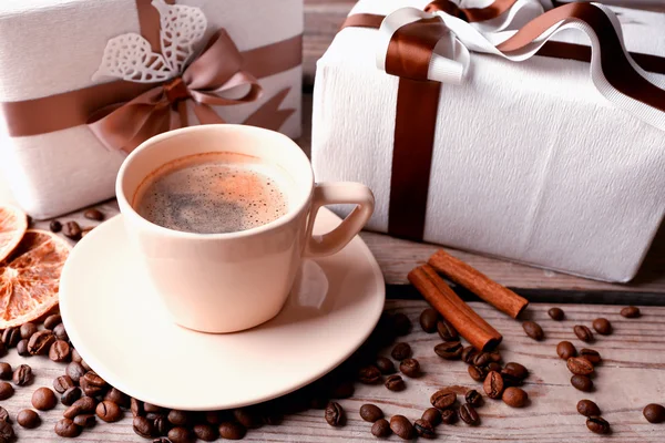 Beautiful gift, cup with coffee and coffee grains on wooden background — Stock Photo, Image