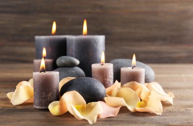 Ahşap arka plan üzerinde çiçek yaprakları ile gri Wax mum yanıyor