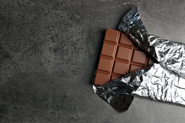 Chocolate bar in foil  on gray background