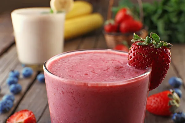 Vasos de batido frío fresco con frutas y bayas, sobre fondo de madera, primer plano — Foto de Stock