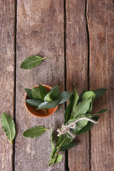 Fresh bay leaves in bowl on vintage wooden table — Stock Photo, Image