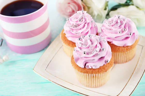 Smakelijke cupcakes op plaat, op lichte achtergrond — Stockfoto