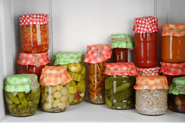 Potten met ingemaakte groenten en bonen op houten plank — Stockfoto