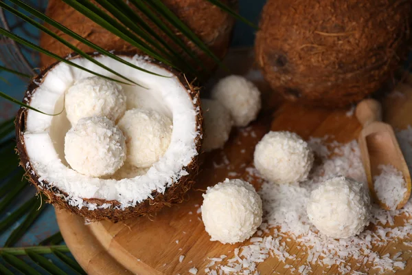 在椰子片和彩色木制背景上的新鲜椰子糖果 — 图库照片