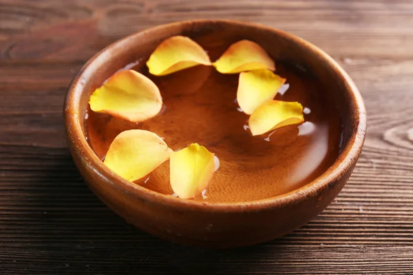 Orange rose petals in a bowl of water on wooden background — Stock Photo, Image