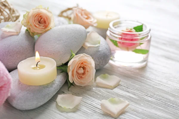 Samenstelling van bloemen, kaarsen en stenen op witte houten achtergrond, in spa salon — Stockfoto