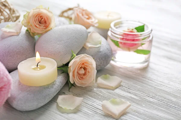 Composición de flores, velas y piedras sobre fondo de madera blanca, en salón spa —  Fotos de Stock