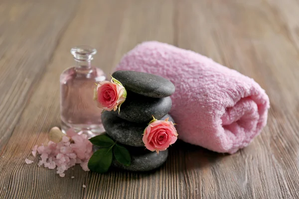 Spa composition of a towel, salt, flowers and stones, on wooden background — Stock Photo, Image