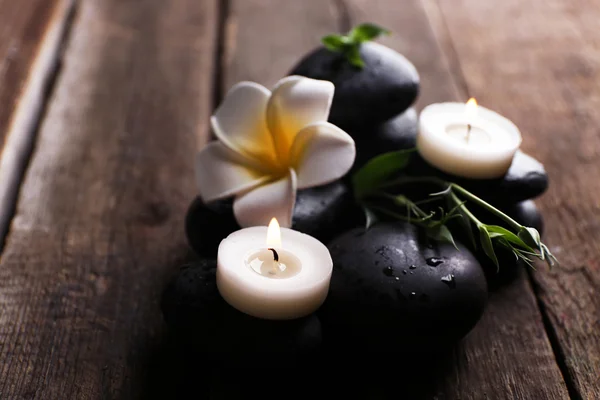 Χαλαρωτικό σύνθεση με εξωτικά fragipani λουλουδιών, βότσαλα και κεριά σε ξύλινα φόντο — Φωτογραφία Αρχείου