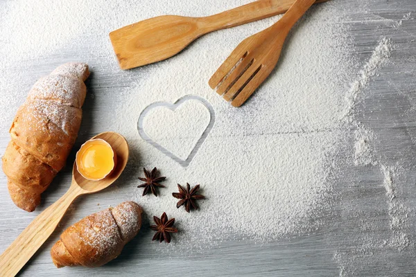 面粉、 羊角面包和木制餐具厨具灰色背景的心 — 图库照片