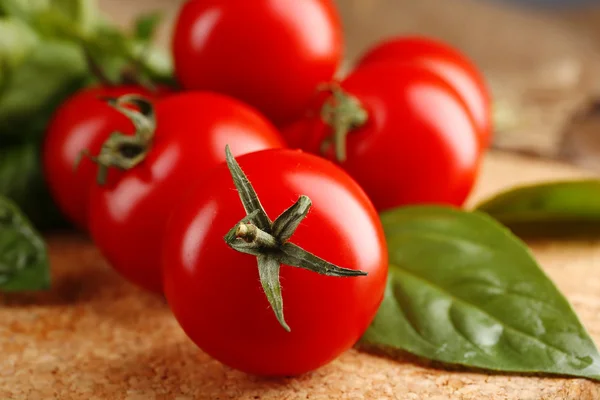 Kerstomaten met basilicum op houten tafel close up — Stockfoto