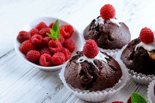 Leckere Schokoladen-Cupcakes mit Beeren und frischer Minze auf Holztisch aus nächster Nähe — Stockfoto