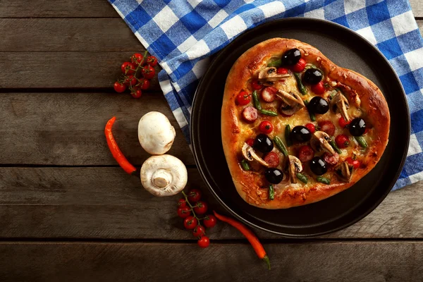 Hart-vormige pizza op pan en blue gecontroleerd katoen servetring op houten achtergrond — Stockfoto