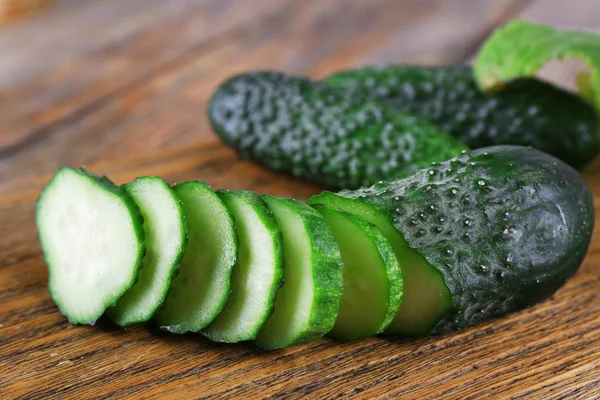 Sliced cucumbers on wooden background — Stock Photo, Image