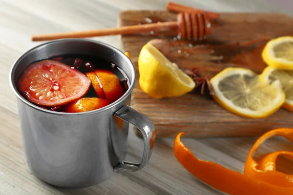 Vinho amontoado em uma caneca com cítricos no fundo de madeira, close-up — Fotografia de Stock