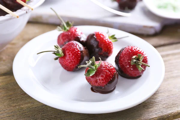 Geserveerd tabel met heerlijke aardbeien in chocolade op houten achtergrond — Stockfoto