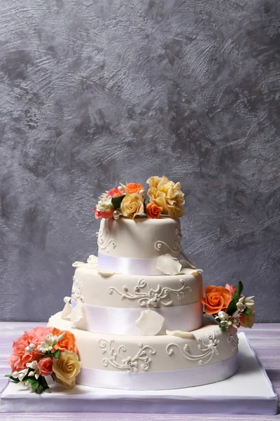 Weiße Hochzeitstorte mit Blumen auf grauem Hintergrund — Stockfoto