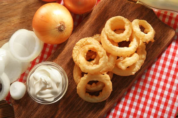 Anillos de virutas con salsa y cebolla en el primer plano de la tabla de cortar — Foto de Stock