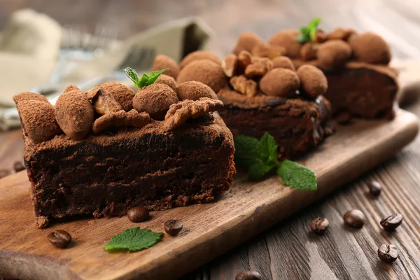 Pedazos de pastel de chocolate con nuez y menta en la mesa, primer plano —  Fotos de Stock