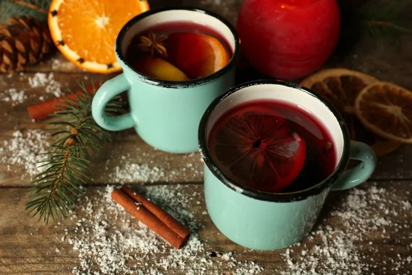 Composición decorada de vino caliente en jarras sobre mesa de madera —  Fotos de Stock