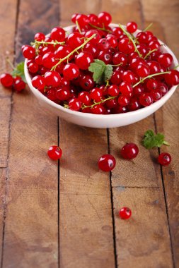 Ahşap masa üzerinde kase taze kırmızı kuş üzümü yakın çekim