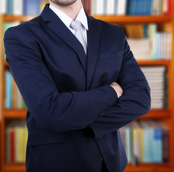 Man in suit on bookshelves background — Stok Foto