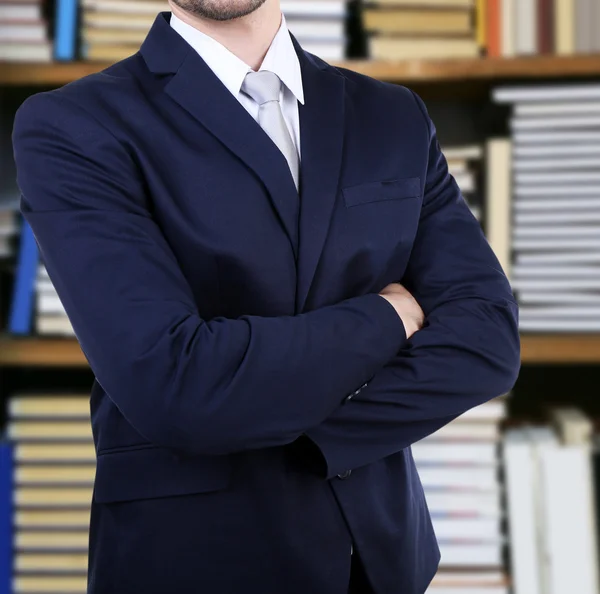 Man in suit on bookshelves background — Stok Foto