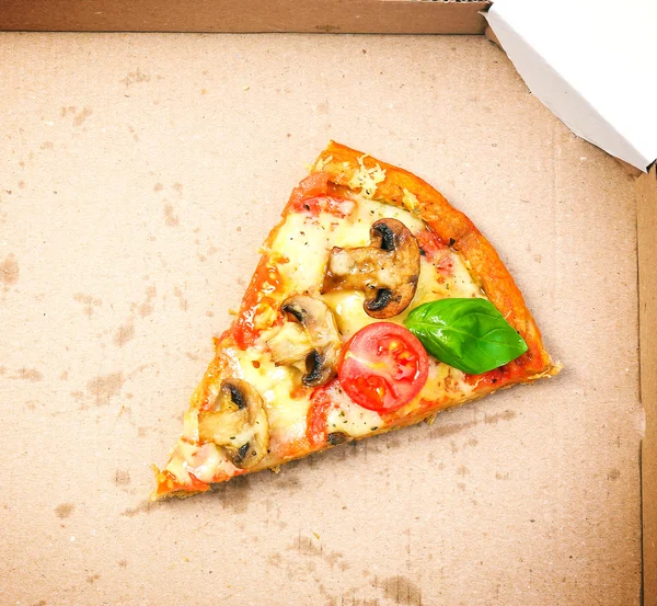 Plak van smakelijke pizza met groenten en basilicum in karton close-up — Stockfoto