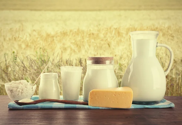 Milchprodukte auf Holztisch vor Feldhintergrund — Stockfoto