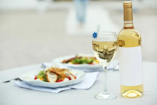 Garrafa de vinho de luxo com salada saborosa na mesa branca servida — Fotografia de Stock