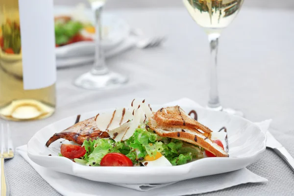 Salade savoureuse avec vin sur table blanche — Photo