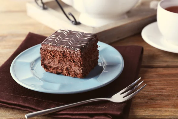 Pastel de chocolate dulce en plato azul con taza de té en servilleta de algodón marrón, de cerca —  Fotos de Stock