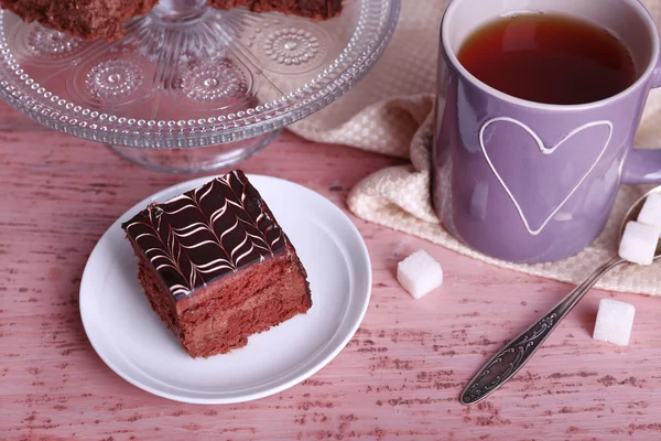 Served table with a cup of tea and chocolate cake on wooden background close-up — Stock Photo, Image