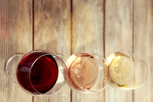 Óculos com vinho branco, rosa e tinto sobre fundo de madeira — Fotografia de Stock