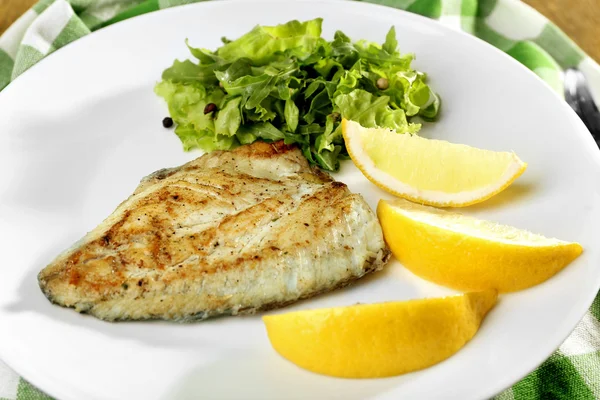 Plat de filet de poisson avec verdure et citron sur assiette fermer — Photo