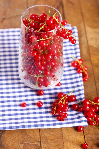 Groselhas vermelhas frescas em vidro na mesa de perto — Fotografia de Stock