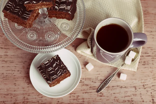 Mesa servida con una taza de té y pastel de chocolate sobre fondo de madera —  Fotos de Stock