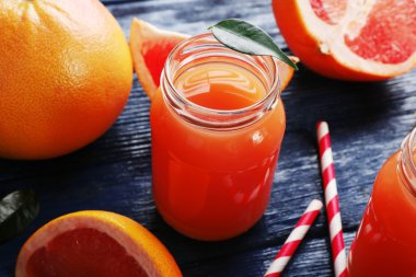 Greyfurt suyu şişeleri ve koyu mavi ahşap zemin üzerine taze meyve