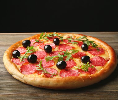 Salam ve zeytin ahşap masa siyah arka plan üzerinde lezzetli pizza