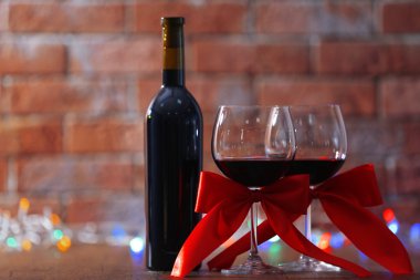 Kırmızı şarap ve Noel ışıkları duvar tuğla zemin üzerine ahşap masa Noel süsler