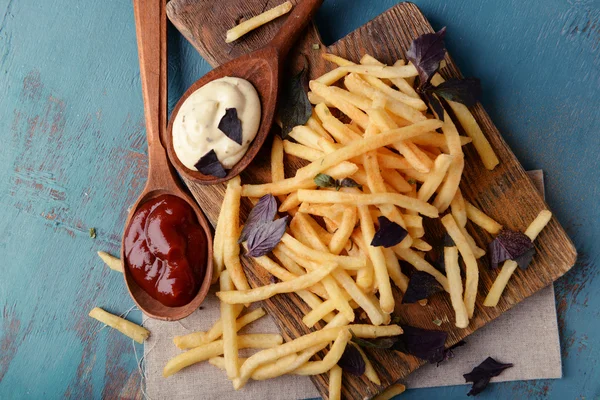 Frans gebakken aardappelen met saus op snijplank — Stockfoto
