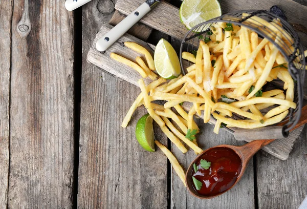 Papas fritas en canasta de metal con salsa y lima en la tabla de cortar —  Fotos de Stock