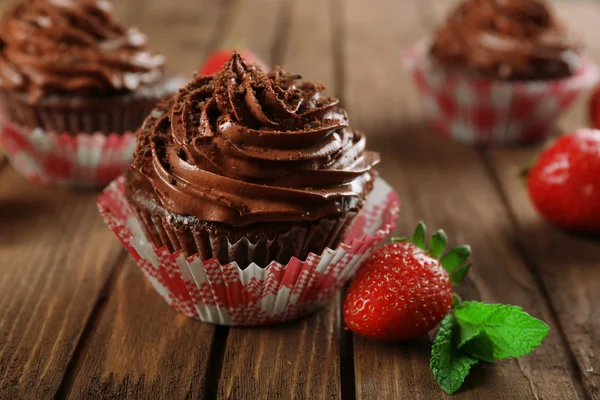 Cupcakes au chocolat et fraises sur fond en bois — Photo