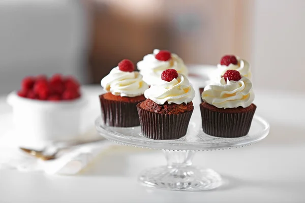 Hermosos cupcakes de chocolate con crema y frambuesa en la mesa — Foto de Stock