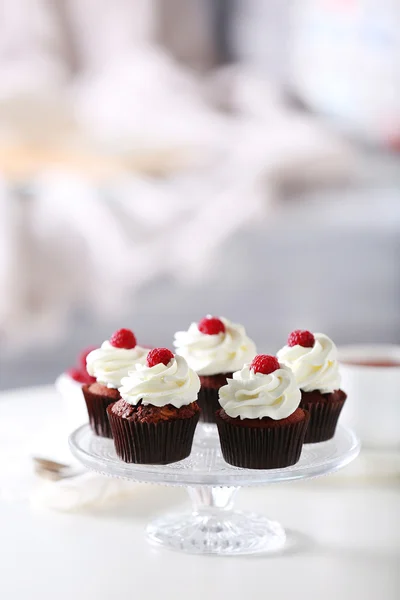 Hermosos cupcakes de chocolate con crema y frambuesa en la mesa — Foto de Stock