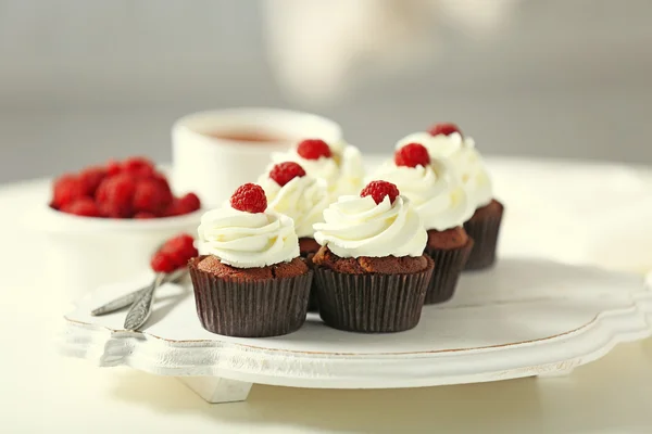 Belos cupcakes de chocolate com creme e framboesa na mesa — Fotografia de Stock